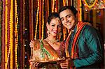 Couple holding a plate of oil lamps on Diwali