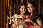 Female friends holding oil lamps on Diwali