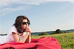 Girl with sunglasses lying on blanket in meadow