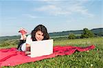 Girl using laptop in meadow