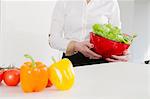 Woman holding bowl of lettuce in kitchen