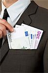 Businessman grasping in jacket pocket with Euro notes