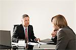 Two businessmen at desk talking