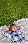 Young man relaxing on blanket in meadow