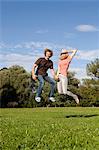 Enthusiastic young couple jumping in meadow