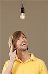 Smiling man in yellow polo shirt looking at light bulb