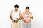 Man holding watermelon next to pregnant woman