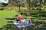 Man and pregnant woman on a blanket in a park