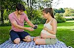 Man taking photograph of pregnant woman in a park