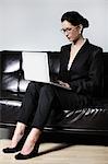 Businesswoman using laptop on couch