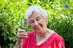 Smiling old woman holding glass of water