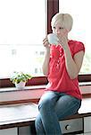 Young woman drinking tea from cup in kitchen