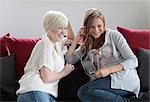 Two happy young women sharing MP3 player on couch