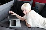 Smiling young woman using laptop on couch