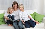 Mother with two children reading book on couch