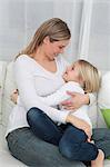 Mother and daughter cuddling on couch