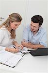 Man and woman sitting at table with file, calculator and laptop