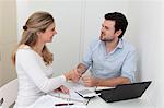 Man and woman shaking hands at table with file, calculator and laptop