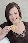 Brunette young woman eating a cookie, portrait