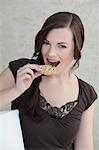 Brunette young woman eating a cookie