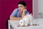 Young woman at table with piggy bank