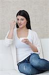 Dark-haired young woman eating yogurt