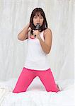 Young woman holding hairbrush singing in bed