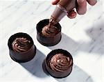 Filling the chocolate timbales with chocolate mousse using a piping bag
