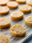 Placing the slices of cooie dough on a baking tray covered in wax paper