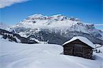 A snow covered wooden barn at the Alta Badia ski resort with Lavarella and Contourines mountains in the background, Dolomites, South Tyrol, Italy, Europe