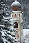 The bell tower of the Church of San Casiano surrounded by snow covered trees, Dolomites, South Tyrol, Italy, Europe