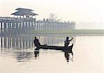 Fisherman on Taungthaman Lake in mist at dawn with U Bein Bridge, the world's longest teak foot bridge spanning 1300 yards, Amarapura, near Mandalay, Myanmar (Burma), Asia