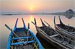 Traditional rowing boat moored on the edge of flat calm Taungthaman Lake at dawn with the colours of the sky reflecting in the calm water, close to the famous U Bein teak bridge, near Mandalay, Myanmar (Burma), Asia