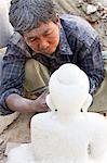 Local man carving a marble Buddha image using an angle grinder, and covered in white marble dust, stone carver's district, Amarapura, near Mandalay, Myanmar (Burma), Southeast Asia