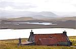 Farmhouse with red iron roof overlooking lochs and mountains off the A858 south of Carloway, Isle of Lewis, Outer Hebrides, Scotland, United Kingdom, Europe