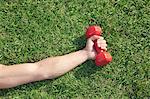 Close Up on Hand Holding Red Dumbbell in Grass