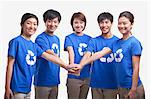 Five young people in recycling t-shirts with hands together, studio shot