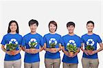 Group of people holding plants, studio shot