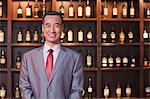 Smiling Businessman Standing by Wine Bottles, Portrait