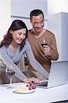 Mature Couple Looking at Laptop in the Kitchen, Drinking Wine