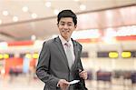 Young businessman holding ticket at the airport, Beijing, China