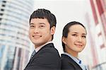 Young business man and woman standing back to back