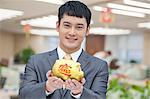 Young business man holding Chinese piggy bank, portrait