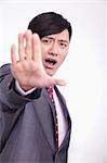 Young businessman with hand raised in stop gesture, studio shot