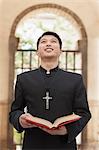 Young Priest Looking to Sky in Front of Doorway