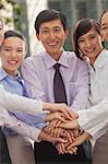 Group of cheerful young business people with hands on top of each other