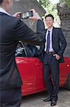 Businesswoman Taking Businessman's Picture Next to His Car