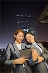 Young businesswomen looking at digital tablet and walking