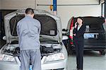 Woman Talking on Phone While Mechanic Fixes Her Car