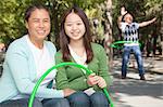 Granddaughter with grandparents playing with plastic hoop in the park